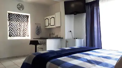 a bedroom with a blue and white bed and a kitchen at 13th Avenue Guesthouse Benoni in Benoni