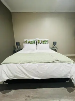 a bedroom with a large bed with white sheets and pillows at Grace Gardens - Grace in Pretoria