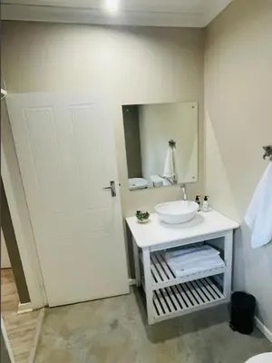 a bathroom with a white sink and a mirror at Grace Gardens - Grace in Pretoria
