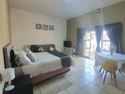 a bedroom with a bed and a table and a window at Koi Inn in Hartbeespoort