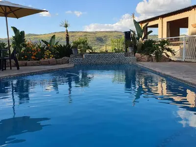 a swimming pool with blue water in front of a house at Koi Inn in Hartbeespoort