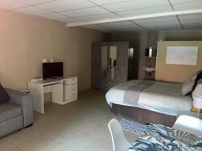 a bedroom with a bed and a tv and a couch at Koi Inn in Hartbeespoort