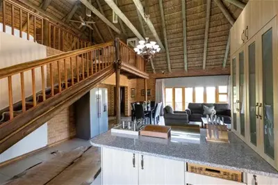 a large room with a staircase and a living room at Lichenry Bush Lodge in Mokopane