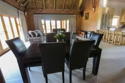 a dining table and chairs in a living room at Lichenry Bush Lodge in Mokopane