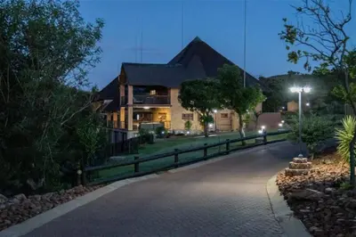 a large house with a fence in front of a driveway at Lichenry Bush Lodge in Mokopane