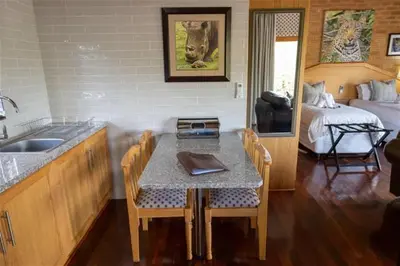a kitchen with a table and a sink and a bed at Lichenry Bush Lodge in Mokopane