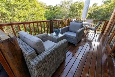 a porch with wicker chairs and a table on a deck at Lichenry Bush Lodge in Mokopane