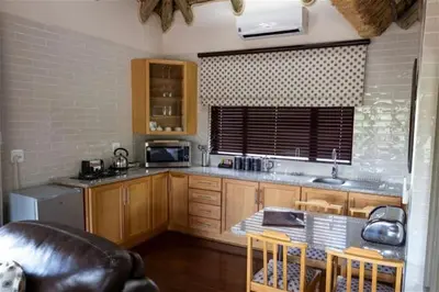 a kitchen with wooden cabinets and a table with chairs at Lichenry Bush Lodge in Mokopane