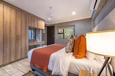 a bedroom with a bed with an orange blanket at Wildheart Safari - Zesty Zebra in Hoedspruit