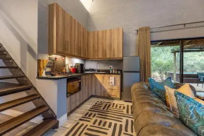 a living room with a couch and a kitchen at Wildheart Safari - Zesty Zebra in Hoedspruit