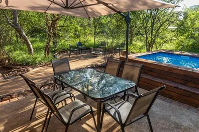 a patio with a table and chairs and a swimming pool at Wildheart Safari - Zesty Zebra in Hoedspruit