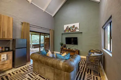 a living room with a leather couch and a television at Wildheart Safari - Zesty Zebra in Hoedspruit