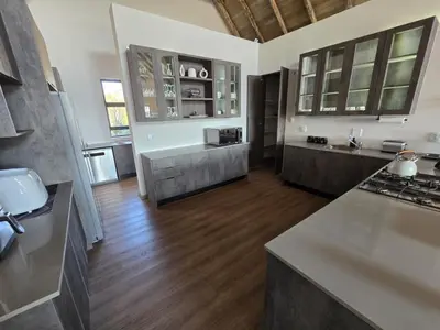 a large kitchen with wooden floors and white walls at Thabanyane Private Lodge Mabalingwe in Bela-Bela