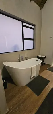 a large white tub in a bathroom with a window at Thabanyane Private Lodge Mabalingwe in Bela-Bela