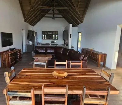 a living room with a wooden table and a couch at Thabanyane Private Lodge Mabalingwe in Bela-Bela