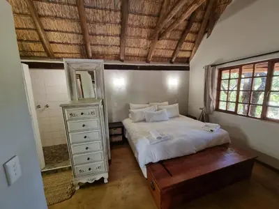 a bedroom with a bed with a dresser and a mirror at Milkwood Cottage Mabalingwe in Bela-Bela