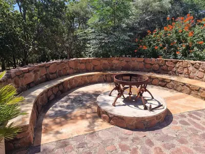 a stone bridge with a table in a garden at Milkwood Cottage Mabalingwe in Bela-Bela