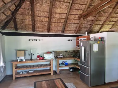 a kitchen with a refrigerator and a wooden table at Milkwood Cottage Mabalingwe in Bela-Bela