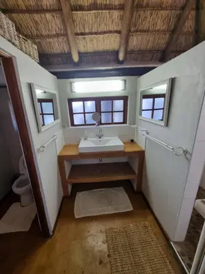 a bathroom with a sink and a toilet and windows at Milkwood Cottage Mabalingwe in Bela-Bela