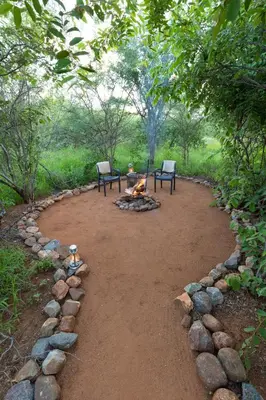 two chairs and a fire pit in a yard at Wildheart Safari - Lion's Den in Hoedspruit