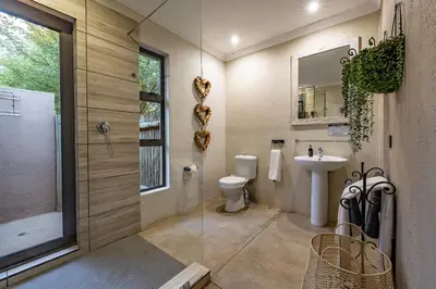 a bathroom with a shower and a toilet and a sink at Wildheart Safari - Lion's Den in Hoedspruit