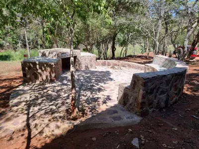 a stone bench in a park with trees in the background at Waterfall Safari Lodge in Winterkamp