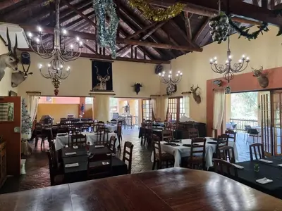 a dining room with tables and chairs and chandeliers at Waterfall Safari Lodge in Winterkamp