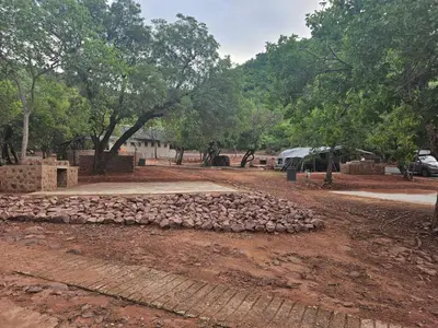 a pile of rocks on the ground in front of trees at Waterfall Safari Lodge in Winterkamp