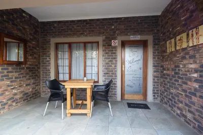 a wooden table and chairs in front of a brick wall at Stevenski's Guesthouse in Lephalale