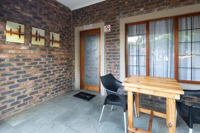 a room with a wooden table and chairs and a brick wall at Stevenski's Guesthouse in Lephalale