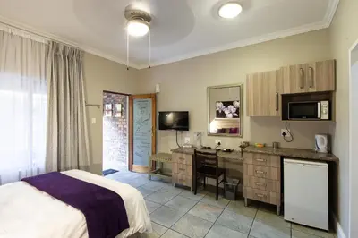 a bedroom with a bed and a desk with a computer at Stevenski's Guesthouse in Lephalale