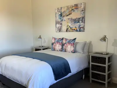 a bedroom with a bed and a painting on the wall at Echo Valley Guest Farm in Breyten