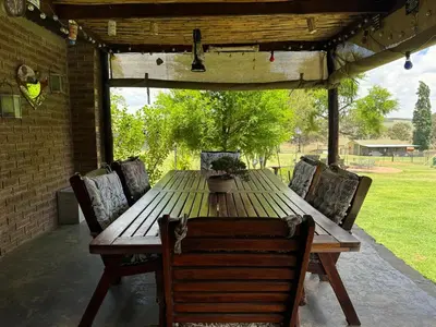 a wooden table and chairs on a patio at Echo Valley Guest Farm in Breyten