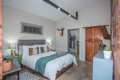 a bedroom with a large bed in a room at Bushbaby Cottage with Tickle Tub in Hartbeespoort in Pretoria