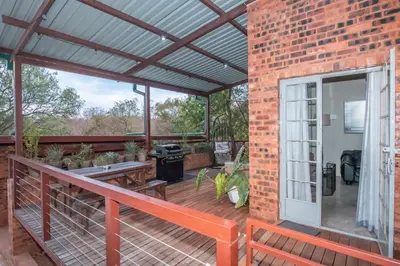 an outdoor patio with a wooden deck with a grill at Bushbaby Cottage with Tickle Tub in Hartbeespoort in Pretoria