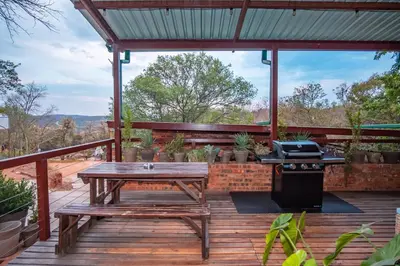 a wooden deck with a picnic table and a grill at Bushbaby Cottage with Tickle Tub in Hartbeespoort in Pretoria