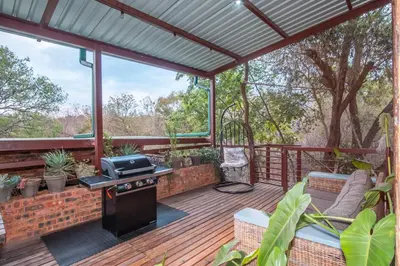 a screened in deck with a grill and a chair at Bushbaby Cottage with Tickle Tub in Hartbeespoort in Pretoria