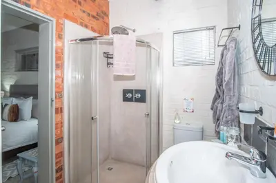 a bathroom with a shower and a sink and a toilet at Bushbaby Cottage with Tickle Tub in Hartbeespoort in Pretoria
