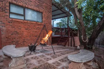 a brick patio with a fire pit and two benches at Bushbaby Cottage with Tickle Tub in Hartbeespoort in Pretoria
