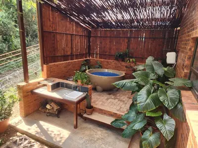 a bathroom with a tub and a table and plants at Bushbaby Cottage with Tickle Tub in Hartbeespoort in Pretoria