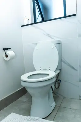 a bathroom with a white toilet with a mirror at Waterfall Apartments Waterfall Cres in Midrand