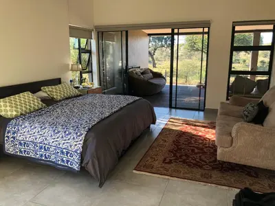 a bedroom with a bed and a living room at Barn Owl Lodge, Mjejane Game Reserve, Greater Kruger Park in Hectorspruit