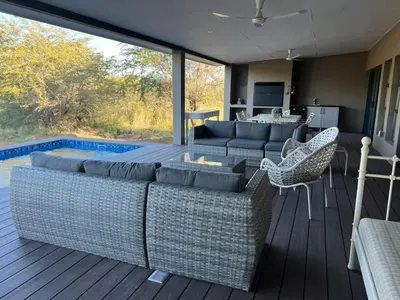 a living room with a couch and chairs on a deck at Barn Owl Lodge, Mjejane Game Reserve, Greater Kruger Park in Hectorspruit