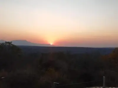a sunset with the sun setting in the horizon at African Sky Bush Camp in Rabelaisruskamp