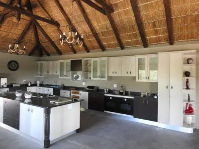 a large kitchen with white cabinets and black appliances at Balule Bushveld Safari Lodge in Phalaborwa