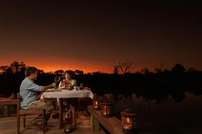 a man and woman sitting at a table drinking wine at Simbavati Waterside in Klaserie Private Nature Reserve