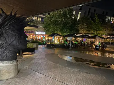 a mall with a statue of a head in a city at night at Menlyn Maine Residences - Kyoto king size xl bed in Pretoria