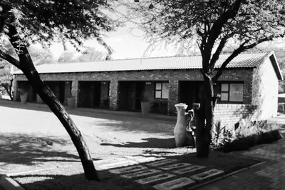 a black and white photo of a building with two trees at Big D Accommodation & guesthouse in Northam