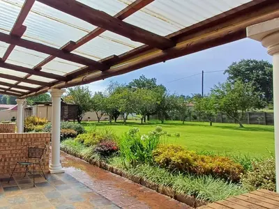 a patio with a pergola and a green yard at Kings B&B in Lake Chrissie