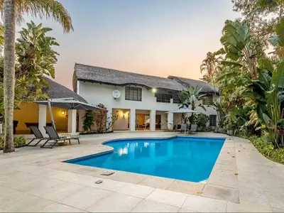 a villa with a swimming pool in front of a house at Royal Bakoena Hamiltonparks Country Lodge in Hazyview